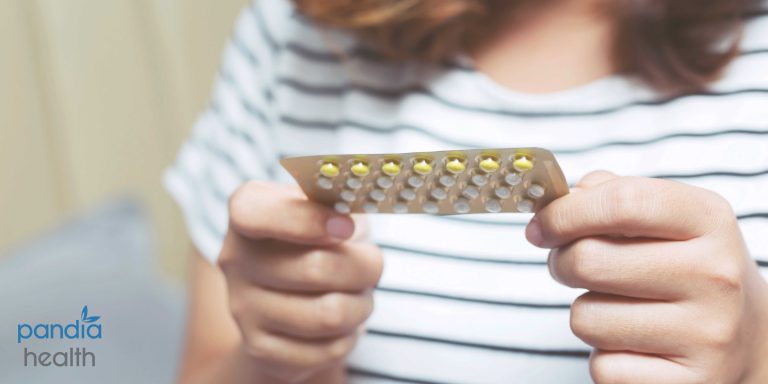 Kobieta trzymająca tabletkę antykoncepcyjną