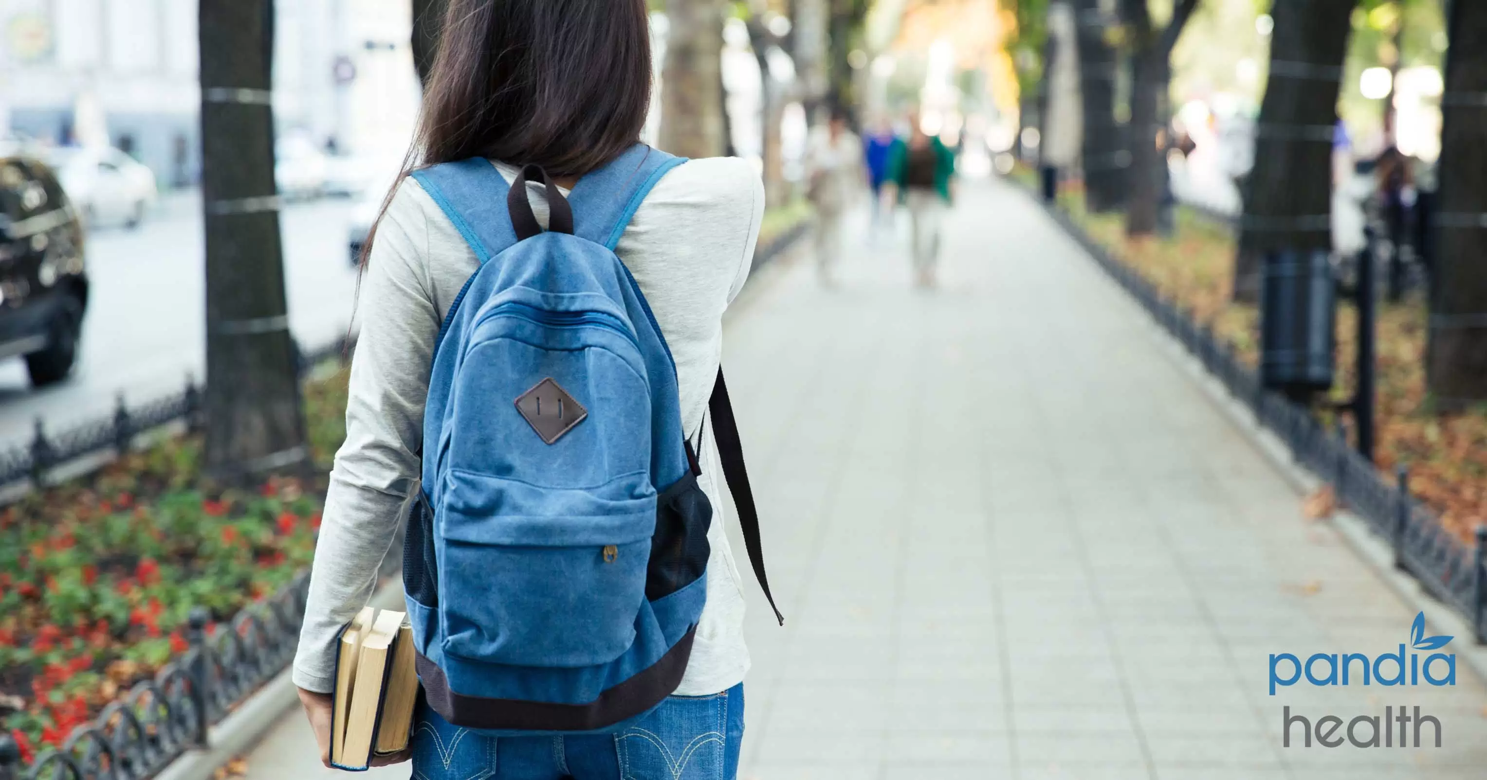 Woman walking with backpack and holding books