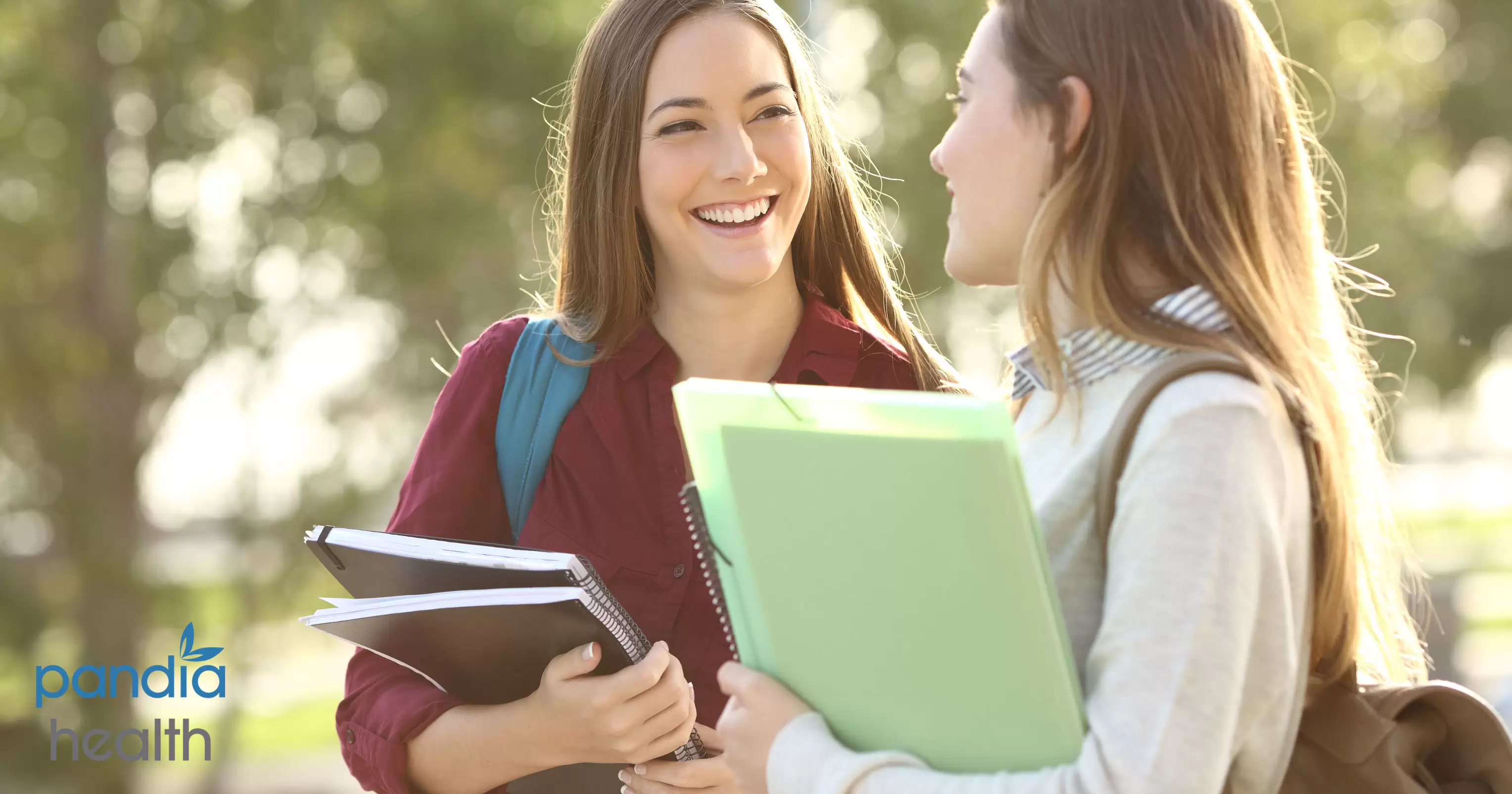 Two school girls holding notebooks and laughing