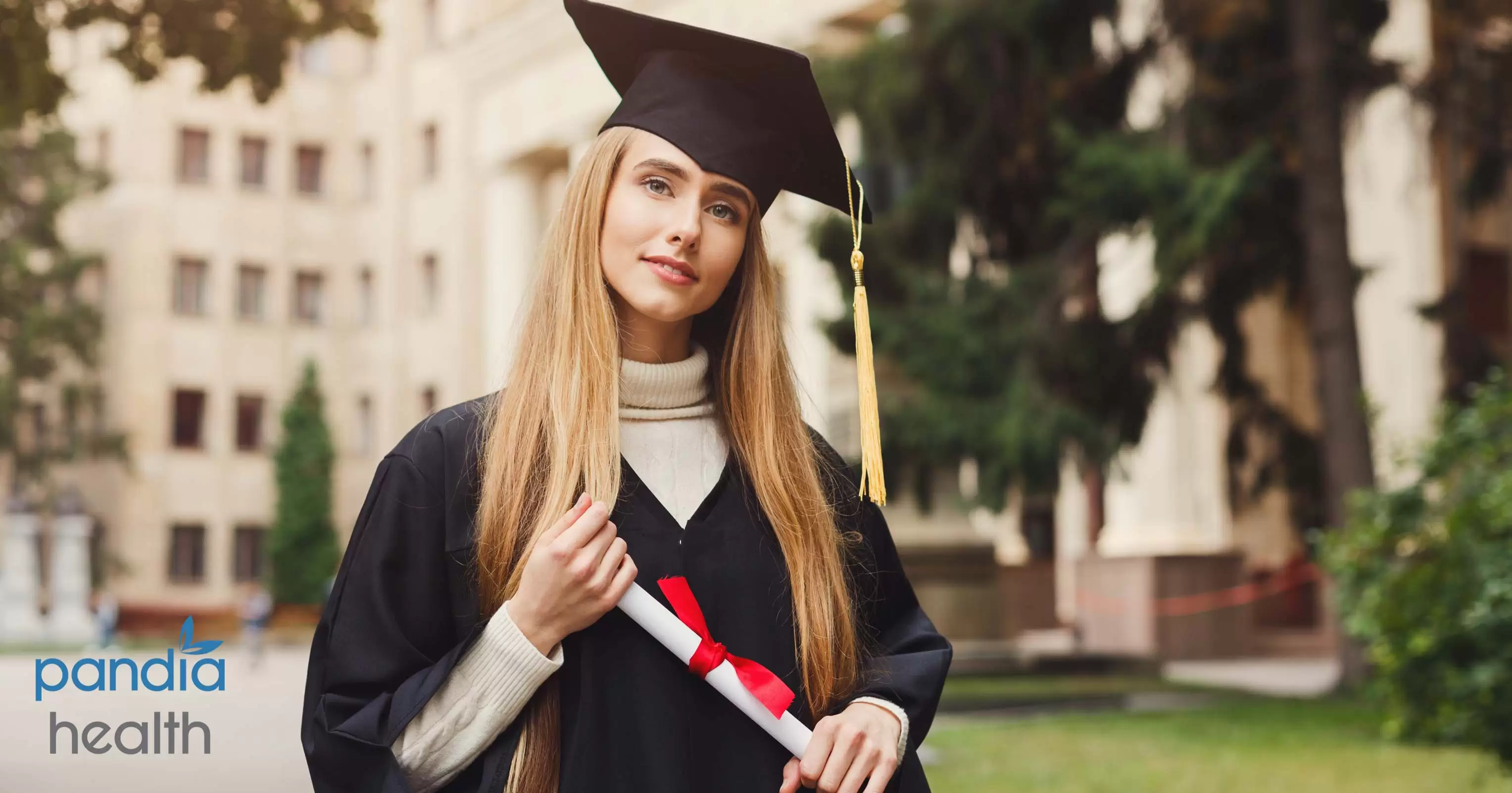 College graduate in black cap and gown holding diploma