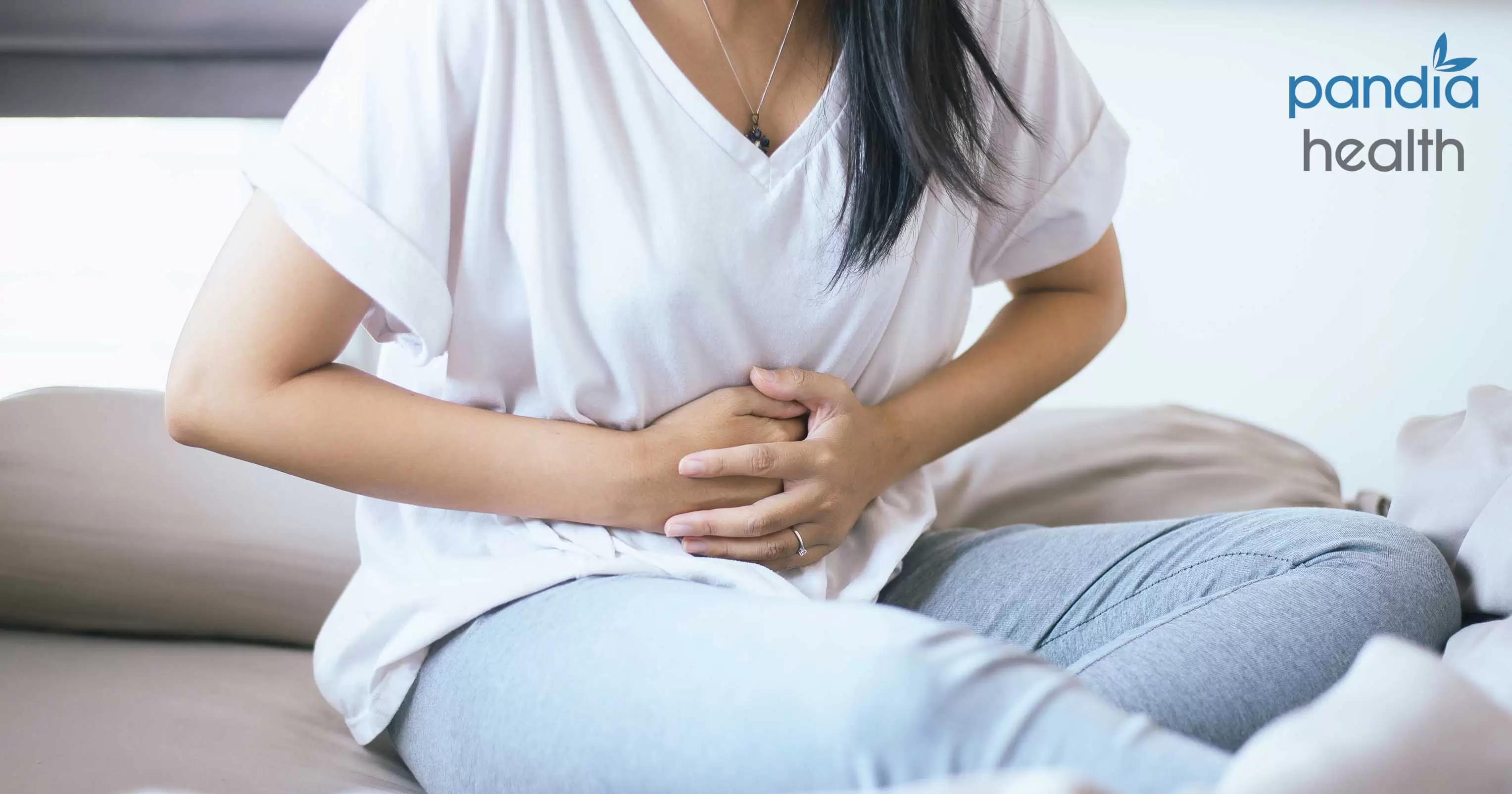 Woman sitting on bed with hand on stomach