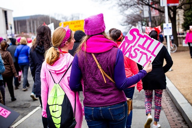 A sign with still nasty on it and a woman with a pussy hat