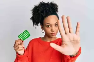 woman holding a birth control pill pack using other hand to show stop