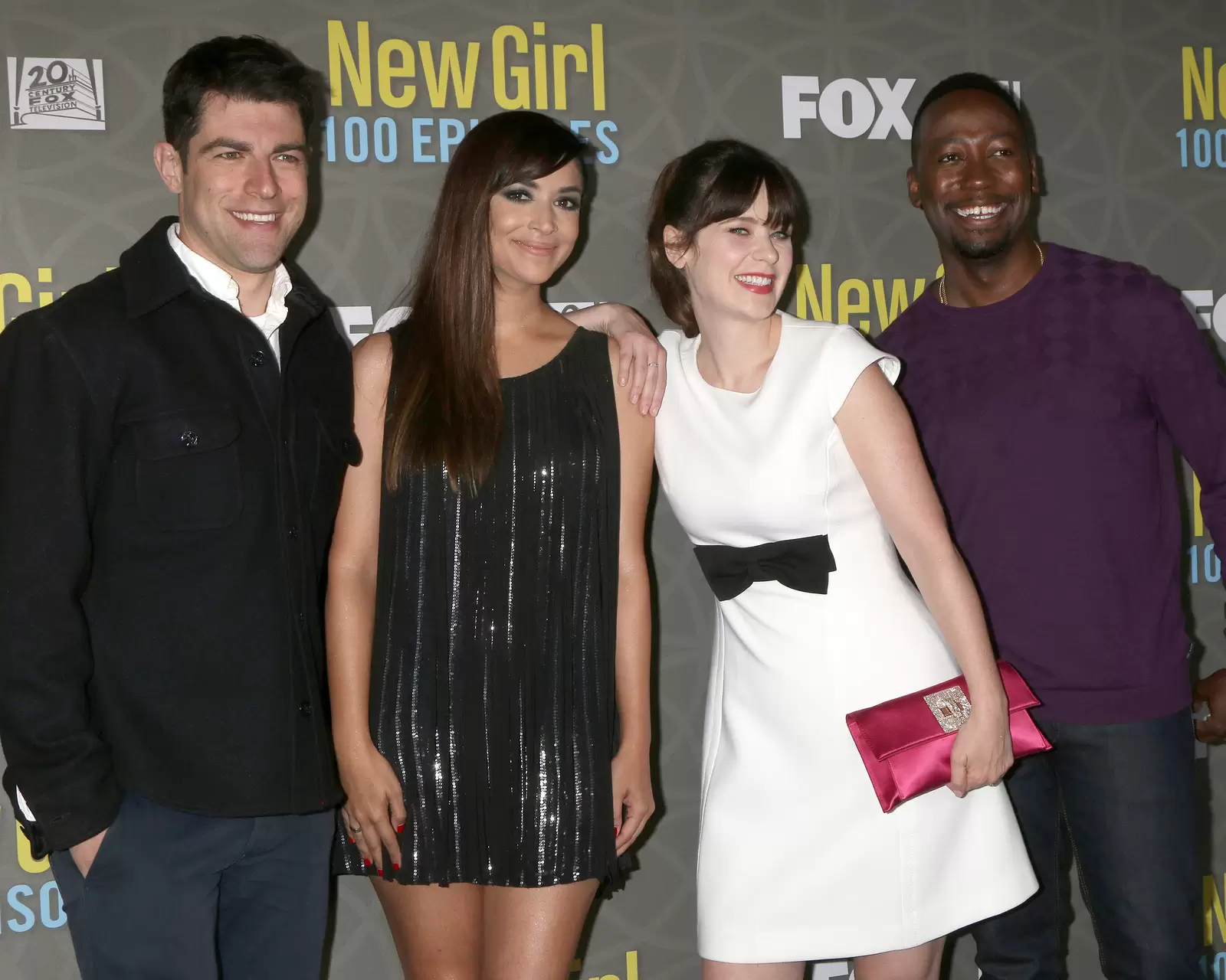 four celebrities smiling at the camera at a press event