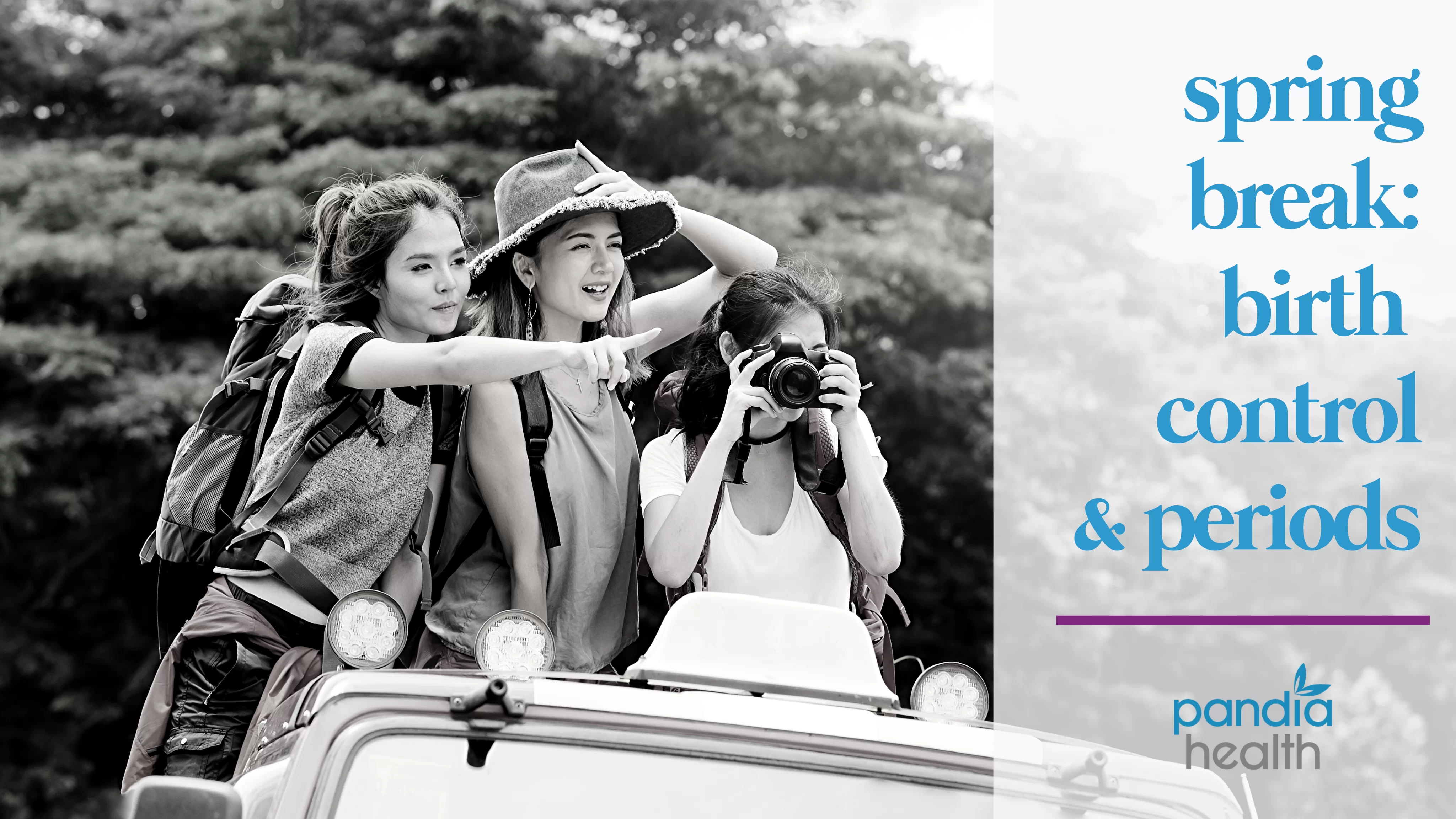 three girls standing up out of a jeep in travel clothes, one pointing and one taking a photo, all smiling, in black and white