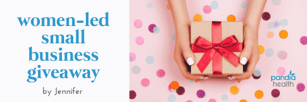 hands presenting a giftbox on a pink table with confetti