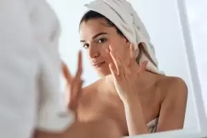 women applying acne treatment on her face