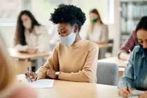 girl wearing mask while writing 