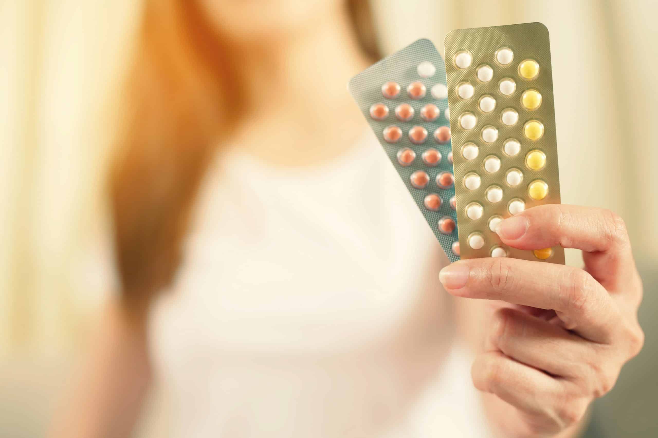 Woman hands opening Aurovela vs Junel birth control pills in hand.