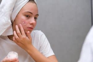women applying cream on acne