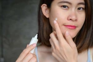 A woman applying Tretinoin cream to her face.