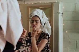 A photo of a woman looking into a mirror and placing her finger on her bottom lip