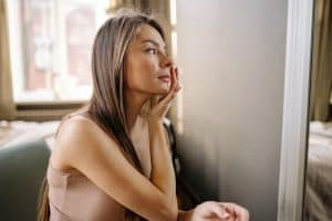 women sitting on the couch applying skin care products to her face