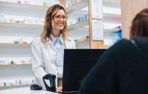 Female pharmacist assisting a patient over the counter in a drug store