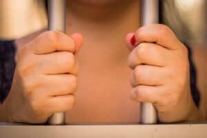 Woman's hands Holding Jail Gaol Cells