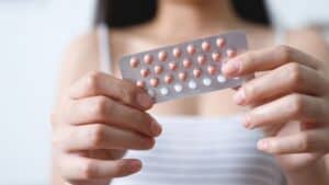  Birth control pack being held with two hands by a young woman in the background