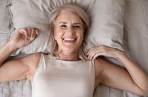 Middle aged woman smiling while laying on her bed