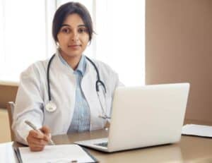 Female doctor wearing a lab coat in front of a laptop