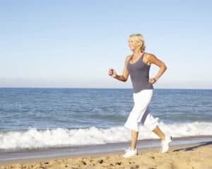 Woman in athleisure clothes running on the beach on a sunny day