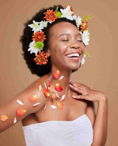 Smiling black woman with a flower crown on a brown background 