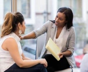 Black woman places hand on female friend’s shoulder