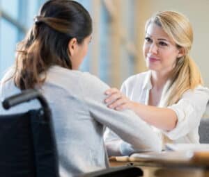 Blonde woman rests her hand on her female friend’s shoulder