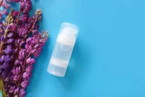 Unbranded transparent bottle of Intimate lubricant gel and purple lupine flower frame